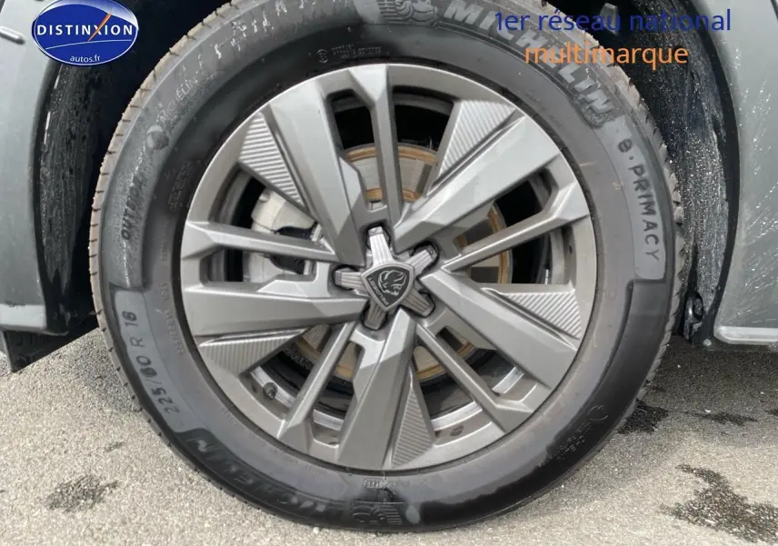 Gros plan sur la roue avant gauche avec jante alu grise du Peugeot 5008 noir Hybrid 145 allure e-dcs6 2025.