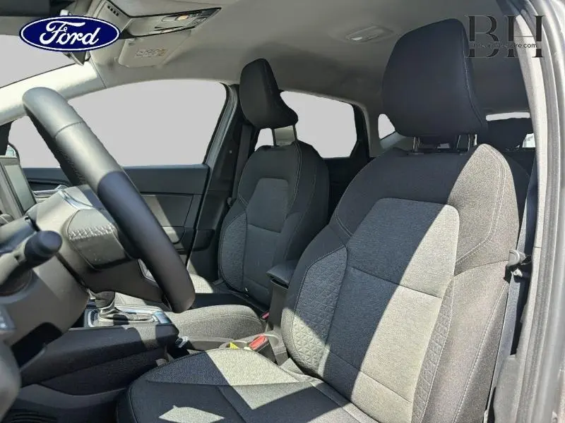Intérieur du Renault Captur 2023, vue côté gauche sur sièges tissu noir et gris avec accoudoir central.