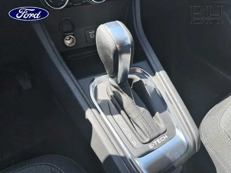 Gros plan sur la commande de boîte automatique noire avec logo E-TECH dans l'habitacle sombre du Renault Captur gris Cassiopée.