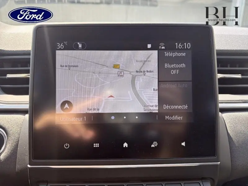 Écran tactile central du tableau de bord du Renault Captur gris Cassiopée, affichant la navigation GPS et les options Bluetooth.