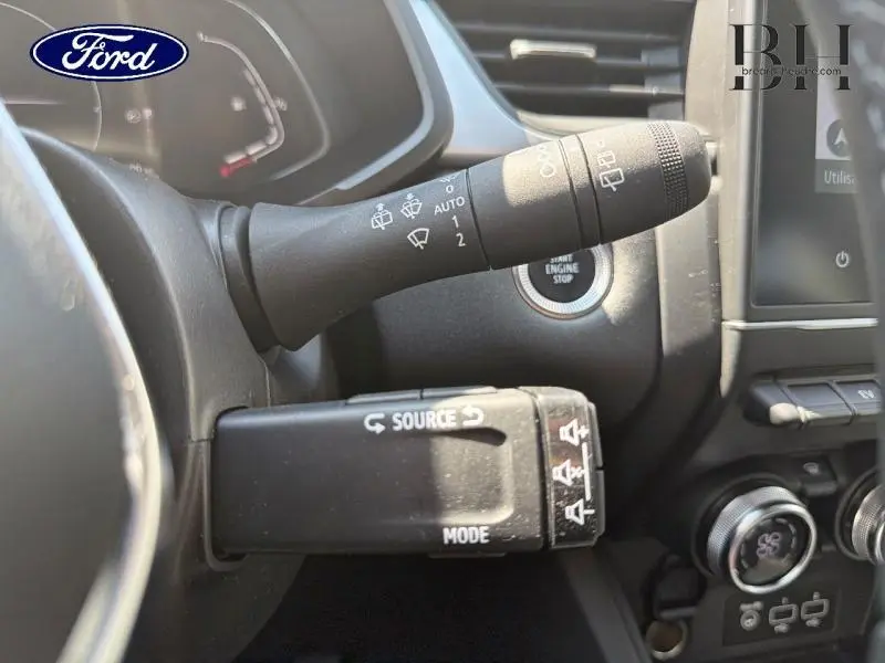 Gros plan sur les commandes au volant et bouton start/stop d’un Renault Captur gris Cassiopée hybride 2023.