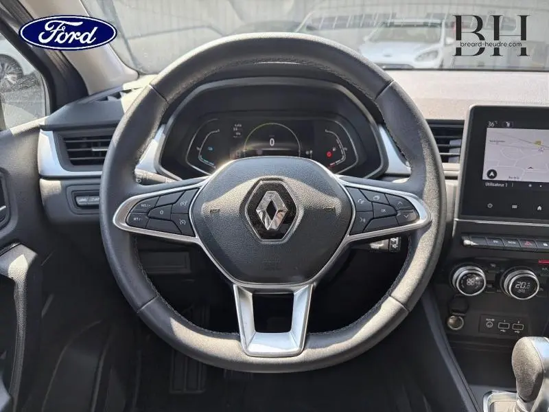 Vue rapprochée du volant noir avec logo Renault au centre et tableau de bord numérique du Renault Captur 2023.