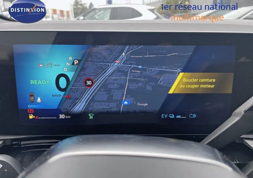 Vue intérieure du tableau de bord numérique du Renault Austral gris métal 2025, affichant la navigation et les alertes de conduite.