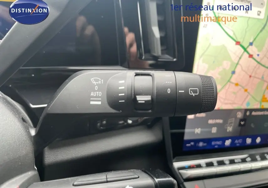 Gros plan sur la commande d’essuie-glace du Renault Austral gris métal 2025, avec écran tactile et carte GPS en arrière-plan.
