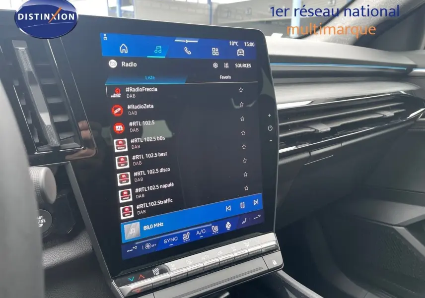 Vue intérieure centrée sur l’écran tactile du tableau de bord du Renault Austral gris métal 2025, affichant la radio DAB.