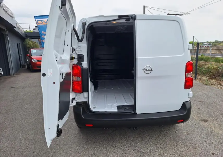 Vue arrière d’un Opel Vivaro blanc 2025 avec porte latérale gauche ouverte, montrant l’espace de chargement vide.