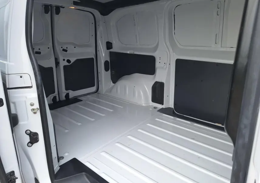 Vue intérieure du fourgon Opel Vivaro blanc, montrant l’espace de chargement vide avec porte latérale ouverte.