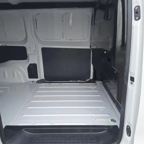 Intérieur du fourgon Opel Vivaro blanc vu de l'ouverture latérale, montrant l'espace de chargement vide et les parois métalliques.