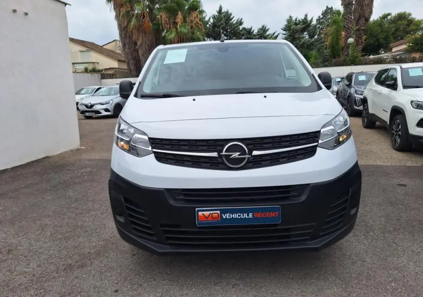 Vue frontale d’un Opel Vivaro blanc avec calandre noire et plaque « Véhicule récent » visible.