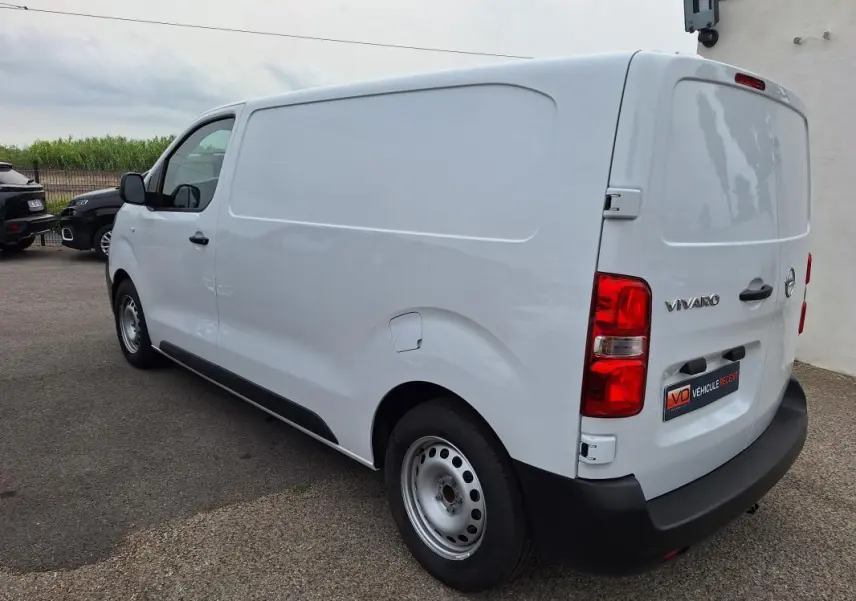 Vue 3/4 arrière droite d'un fourgon Opel Vivaro blanc, avec porte latérale et feux arrière rouges visibles.
