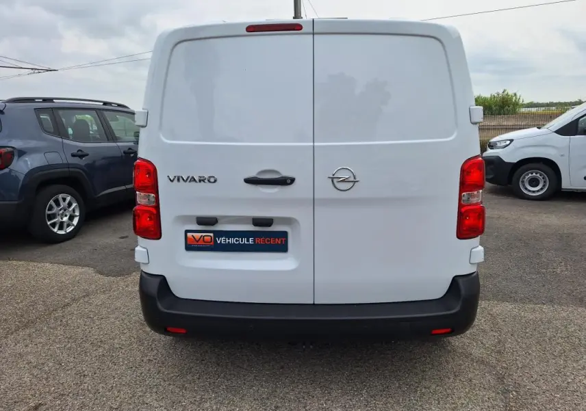 Vue arrière d’un fourgon Opel Vivaro blanc, avec portes battantes fermées et feux rouges visibles.