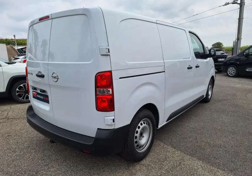 Opel Vivaro blanc vu en 3/4 arrière droit, fourgon utilitaire avec porte latérale et feux arrière rouges.