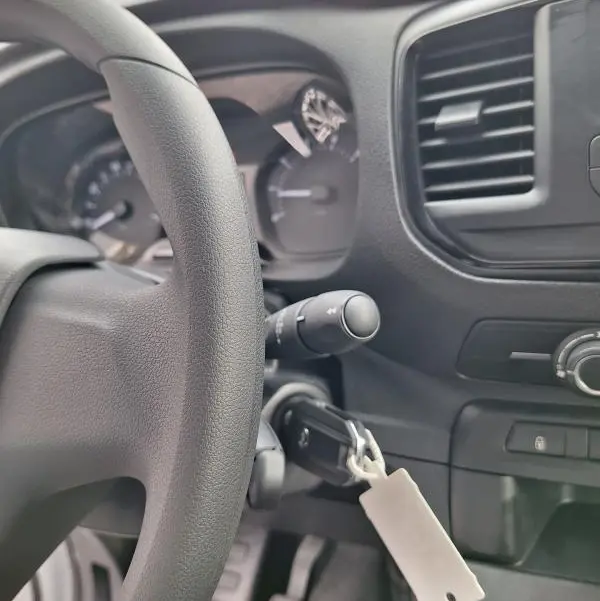 Vue intérieure centrée sur le volant et le tableau de bord noir de l'Opel Vivaro blanc, avec clé insérée dans le contact.