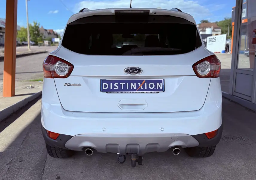 Vue arrière d'un Ford Kuga blanc de 2012 avec double sortie d'échappement et attelage visible.
