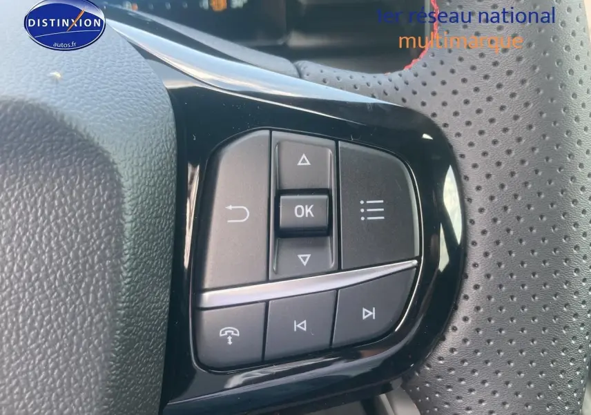 Gros plan sur les commandes multifonctions noires du volant perforé du Ford Puma gris cactus 2025.