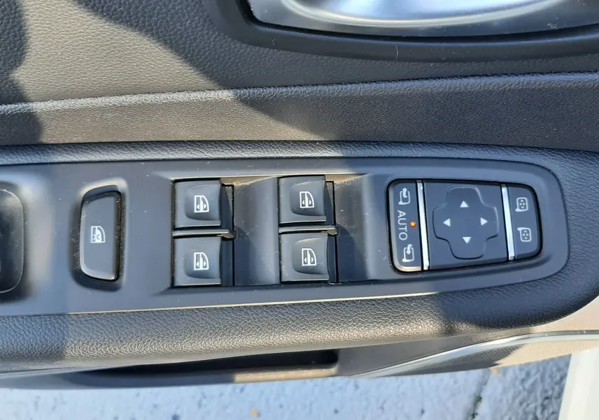 Gros plan sur les commandes de lève-vitres et réglages des rétroviseurs côté conducteur du Renault Captur blanc nacré.