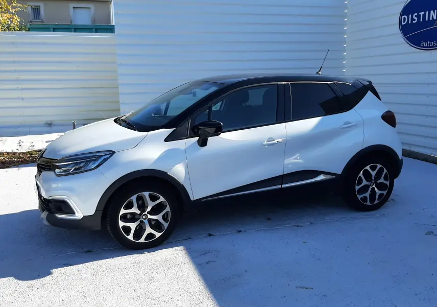 Renault Captur blanc nacré avec toit noir vu de profil côté gauche, soulignant ses jantes alliage et lignes modernes.