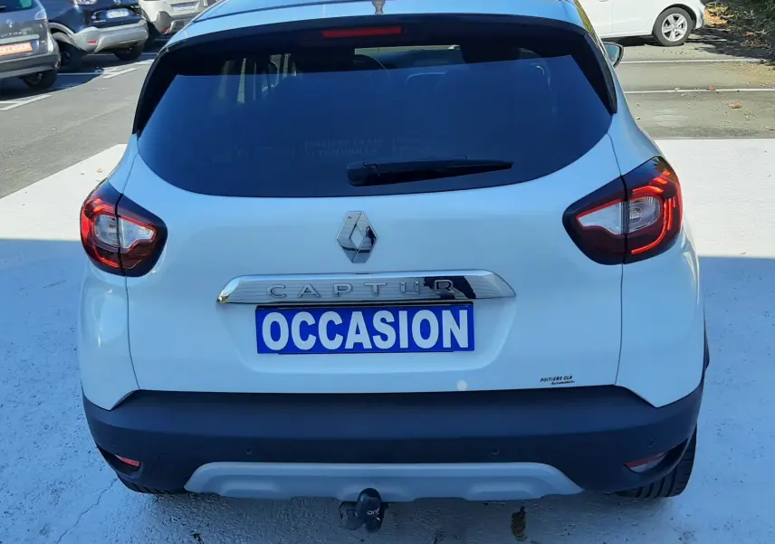 Vue arrière d'un Renault Captur blanc nacré avec toit noir, immatriculé "OCCASION", stationné en extérieur.