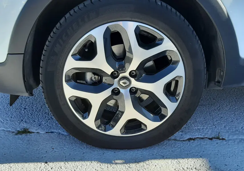 Gros plan sur la roue avant gauche du Renault Captur blanc nacré avec jante alliage bi-ton distinctive.