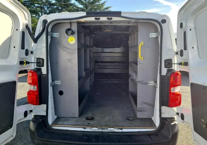 Vue arrière du Peugeot Expert Fourgon blanc 2022 avec portes ouvertes montrant l'intérieur équipé de rangements gris.