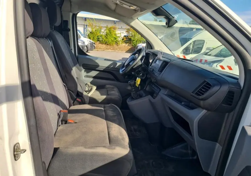 Intérieur du Peugeot Expert Fourgon blanc 2022 vu côté conducteur, montrant sièges et tableau de bord noir.