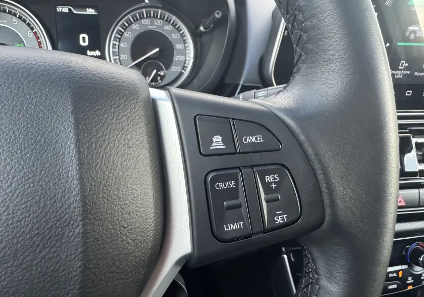 Gros plan sur le volant noir du Suzuki S-Cross 1.4 Style Hybrid 2023, montrant les commandes de régulateur de vitesse.