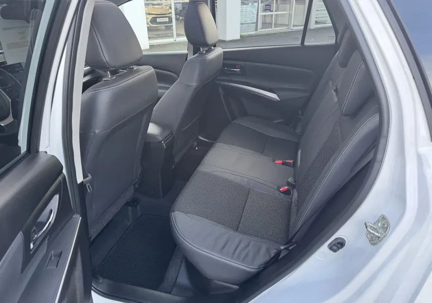Vue côté droit de l'habitacle arrière du Suzuki S-Cross blanc 2023, sièges en cuir noir avec surpiqûres blanches.
