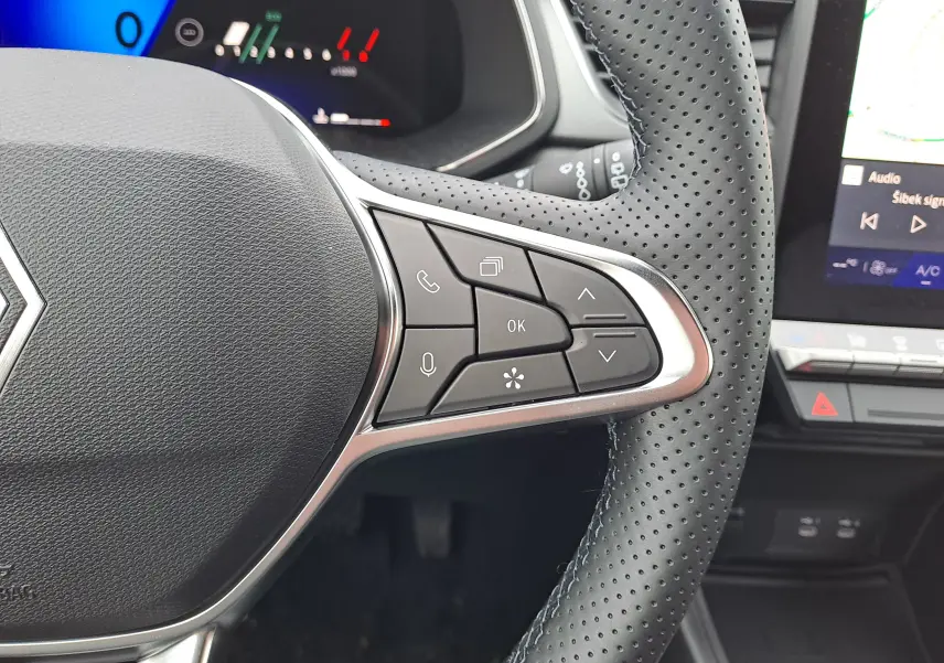 Vue rapprochée du volant perforé noir de la Renault Symbioz avec commandes multifonctions et tableau de bord digital partiel.