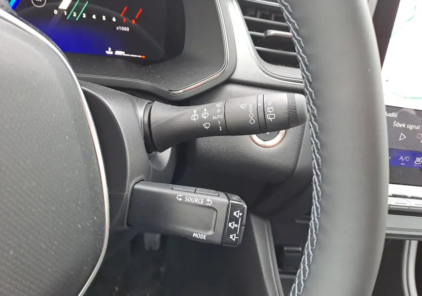 Gros plan sur le volant et commandes au volant du Renault Symbioz bleu Mercure, affichage numérique partiel en arrière-plan.