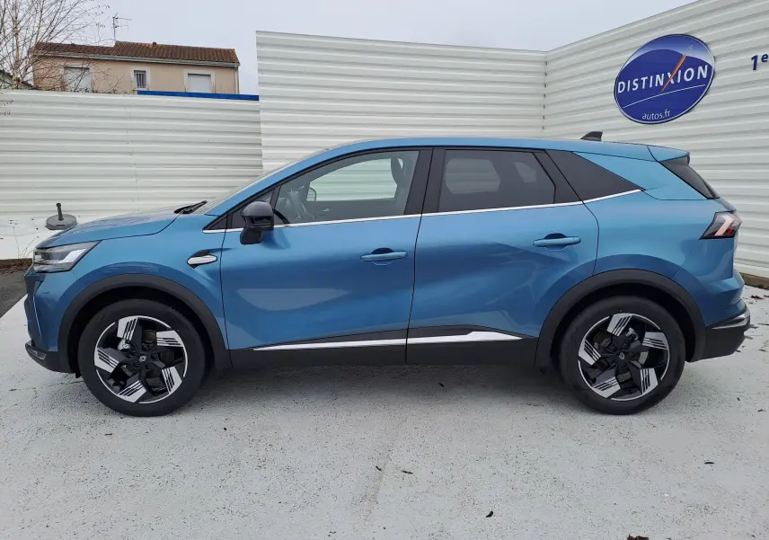 Profil latéral droit d’un Renault Symbioz bleu mercure 2025 avec jantes bicolores et détails chromés sur les portes.