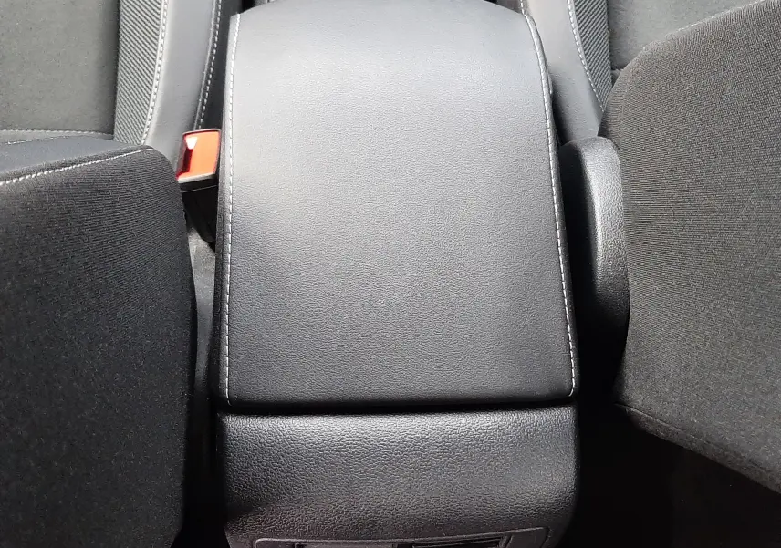 Vue plongeante sur l'accoudoir central noir et les sièges avant du Volkswagen T-Roc gris Pyrite 2023.