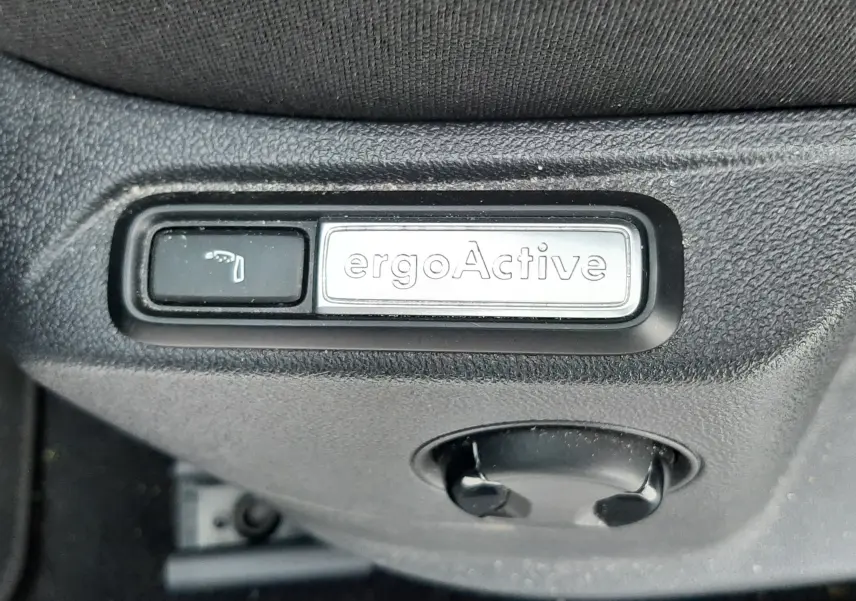 Gros plan sur la commande ergoActive du siège côté conducteur dans l'habitacle du Volkswagen T-Roc gris pyrite.