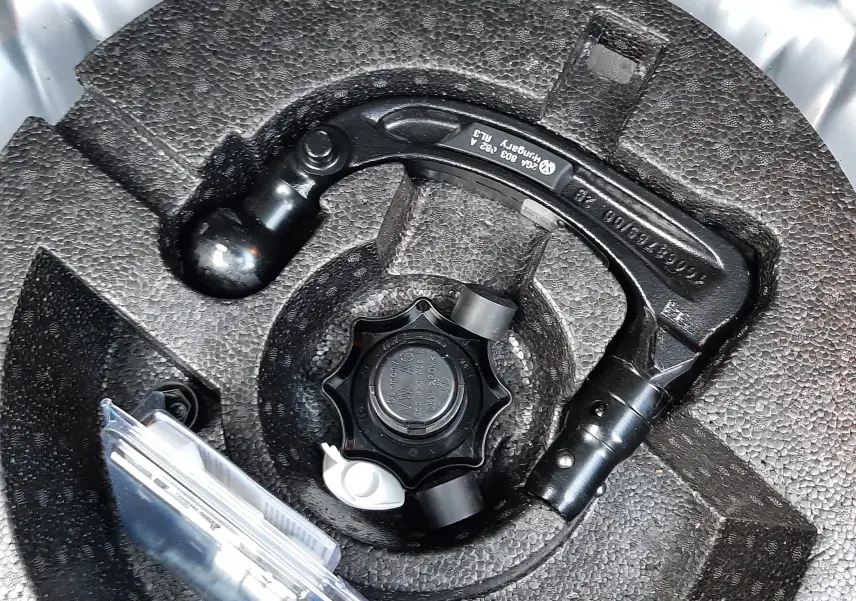 Gros plan sur l'attelage amovible rangé dans le coffre du Volkswagen T-Roc gris pyrite 2023.