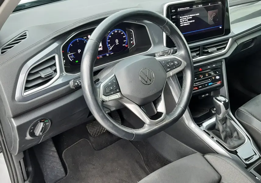 Vue intérieure du poste de conduite du Volkswagen T-Roc 2023, tableau de bord numérique et volant multifonction noir.