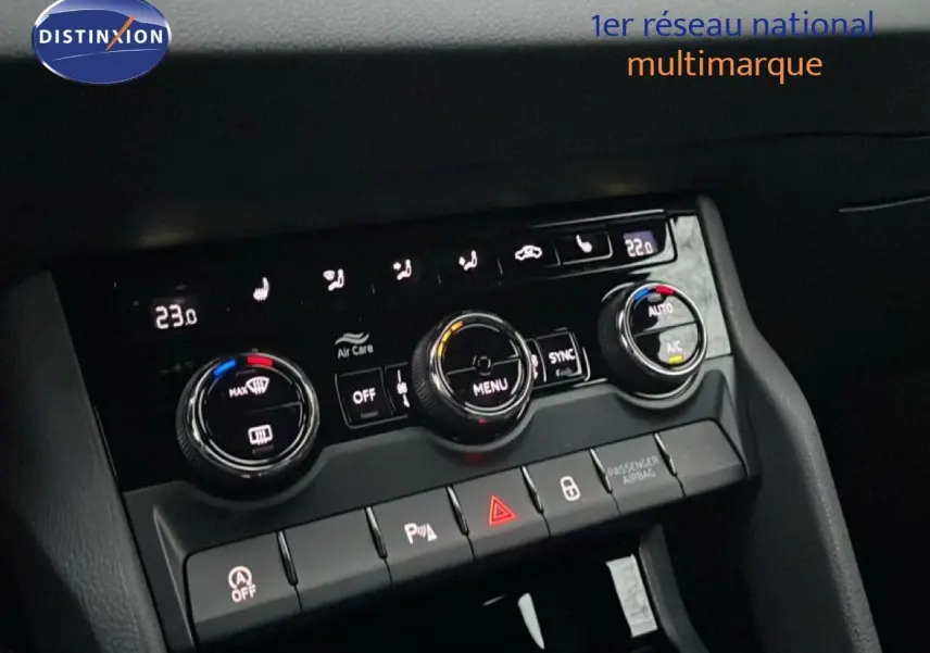 Vue rapprochée du tableau de bord du Skoda Karoq gris argent, avec commandes de climatisation et boutons fonctionnels éclairés.