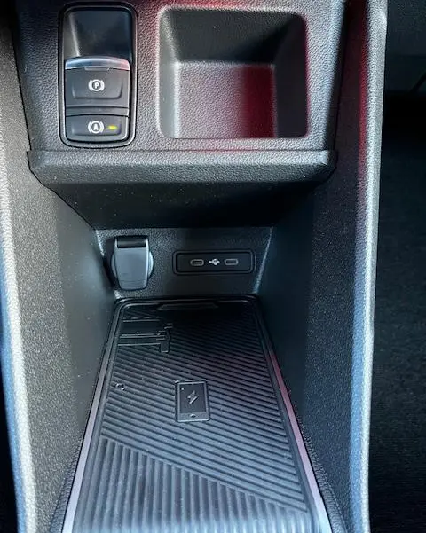 Gros plan sur la console centrale de la Renault R5 Techno jaune 2024, montrant le chargeur sans fil et les ports USB.