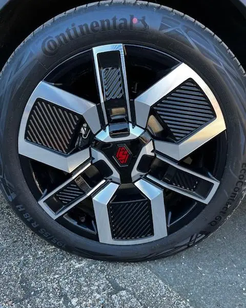 Gros plan sur la jante noire et argentée avec logo rouge du Renault R5 Techno 150 ch jaune, pneu Continental visible.