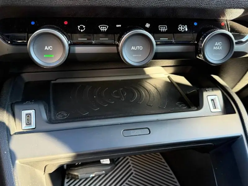 Détail du tableau de bord de la Citroën C4 2024 gris acier, montrant les commandes de climatisation automatique et la zone de recharge sans fil.