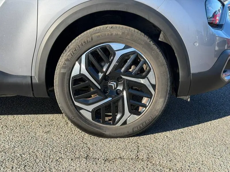 Gros plan sur la roue avant droite d'une Citroën C4 2024 gris acier avec jante alliage au design moderne.