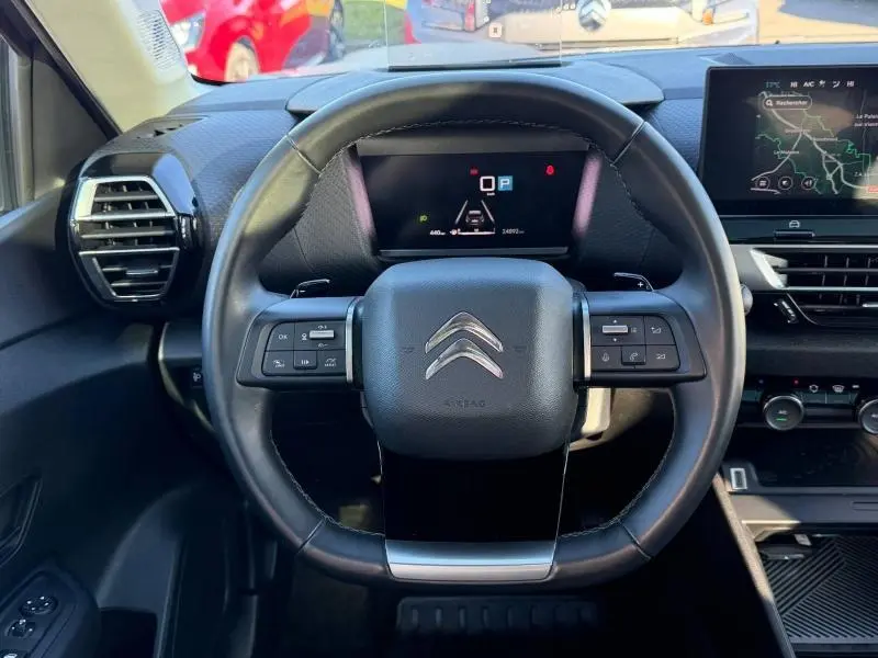 Vue centrée sur le volant cuir noir du Citroën C4 2024 avec tableau de bord numérique et écran tactile à droite.
