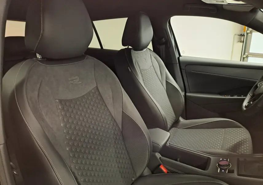 Vue intérieure côté droit montrant les sièges avant en cuir et alcantara avec surpiqûres blanches du Volkswagen T-Roc R-Line noir ébène.