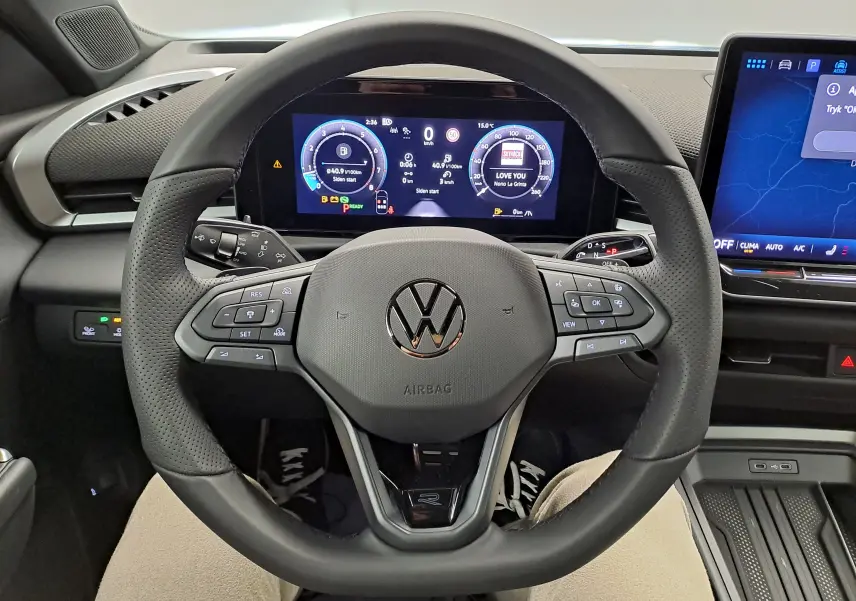 Vue rapprochée du volant noir perforé du Volkswagen T-Roc 2026, avec tableau de bord numérique et écran central tactile.