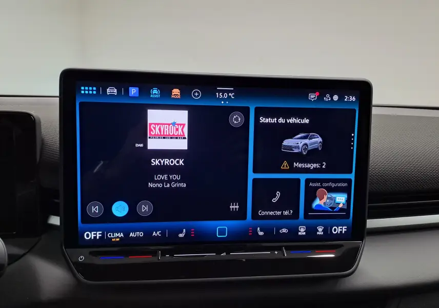 Écran tactile central du Volkswagen T-Roc 2026 affichant la radio et le statut du véhicule, intérieur moderne noir.
