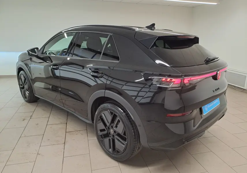 Volkswagen T-Roc 2026 noir ébène en 3/4 arrière droit, jantes noires 19 pouces et feux LED allumés.