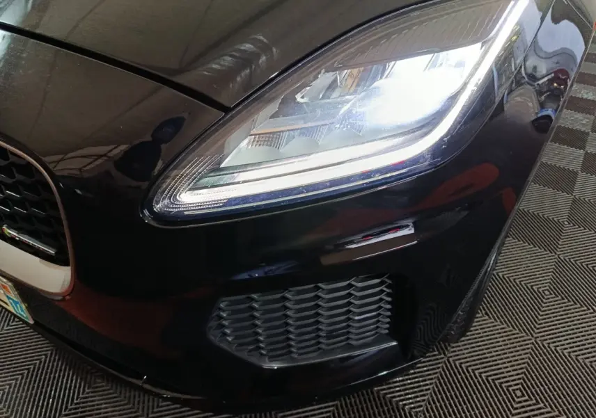 Gros plan sur l'avant droit noir brillant du Jaguar E-PACE 2019, mettant en valeur le phare LED et la calandre.