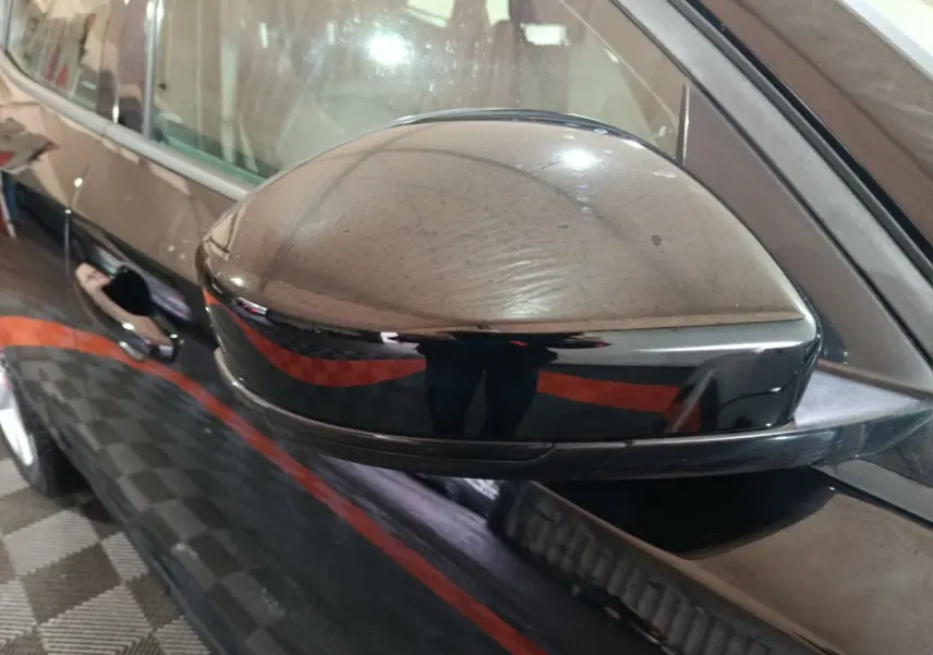 Rétroviseur côté gauche noir brillant du Jaguar E-PACE 2019 avec carrosserie noire en arrière-plan.