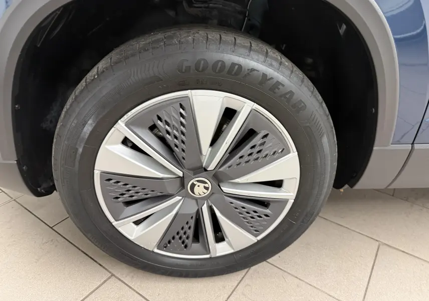 Gros plan sur la roue avant droite du Skoda Karoq bleu lave, avec jante stylisée et pneu Goodyear visible.