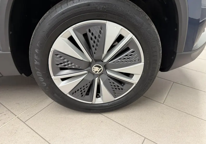 Gros plan sur la roue avant droite du Skoda Karoq bleu lave, jante alliage au design moderne avec logo central.