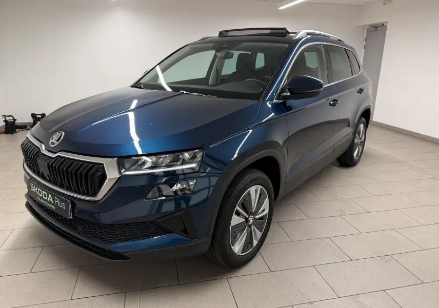Vue 3/4 avant droite d'un Skoda Karoq 2023 bleu lave avec toit ouvrant dans un intérieur neutre.