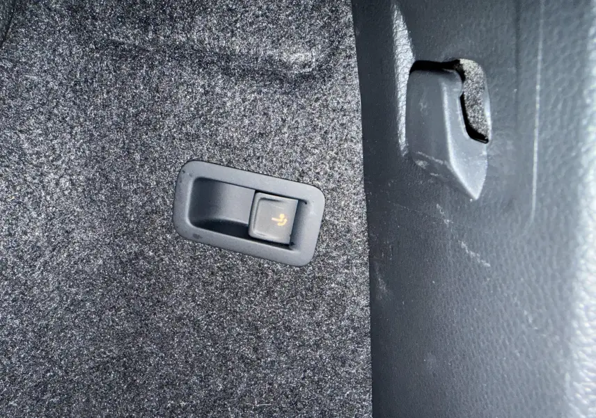 Gros plan sur le bouton de rabattement des sièges dans le coffre du Skoda Karoq 2023 bleu lave.
